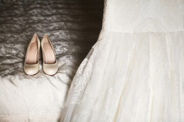 Beige shoes on the bed next to the wedding dress