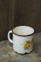 An old metal mug on an old table 