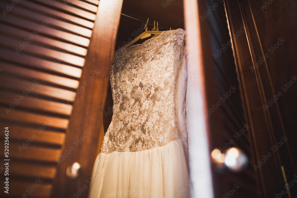 Wall mural wedding dress hanging on a wooden wardrobe