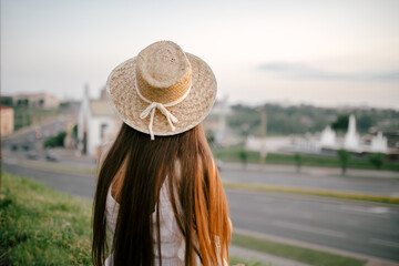 Portrait of a relaxed woman with hat looking forward at the horizon cityscape in the background copy space - 520256685