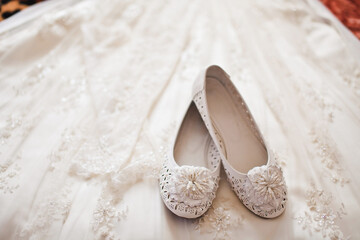 White shoes lie on a wedding dress