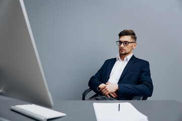 manager wearing glasses works in front of a computer Gray background
