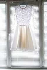 Short wedding dress hanging on the window
