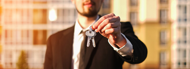 a man bought an apartment in a new building and holds the keys against the backdrop of housing