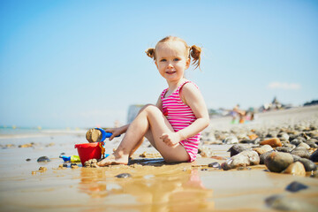 Toddler girl playing on the sand beach at Atlantic coast of Brittany, France