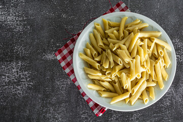 typical italian penne pasta on dark stone background with tomato sauce