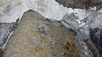 Rest of avalanches in spring with the river having found its way through it and a big rock shaping the scene