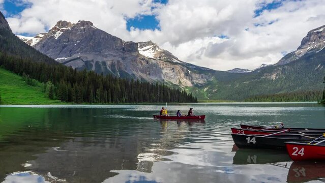 Timelaspe of tourists kayaking in Emerald lake British Columbia Canada in a summer sunny day. colorful boats   and crystal clear lake. reflection of mountains n clouds sky on water surface. panoramic
