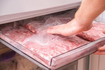 A man puts minced pork and beef in the freezer in serving bags for long storage.