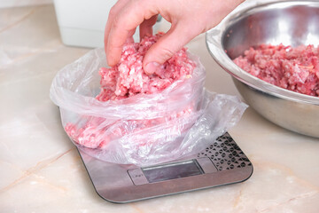A man lays out portioned pork and beef minced meat on the scales in bags for storage in the freezer.