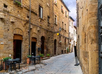Papier Peint photo autocollant Ruelle étroite Une ruelle étroite pittoresque avec des tables de café-terrasse dans le centre historique médiéval de la ville toscane de Volterra.