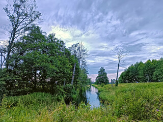 Storm Rainy weather. Summer overcast sky. Small river in wood. Dramatic landscape, cloudy day.