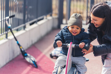 Good looking caucasian woman at the playground with her small african son having the time of their...