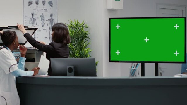 Waiting area and reception desk with greenscreen on tv display, hospital lobby in facility. Chroma key copyspace with isolated mockup background and blank template on monitor, healthcare.