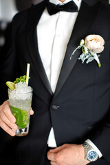 Groom with cocktail and boutonniere at wedding