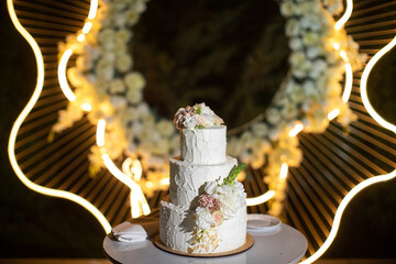Multilevel wedding cake on the table decorated with roses
