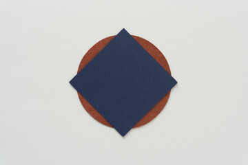 blue paper square (diamond orientation) on a brown circle