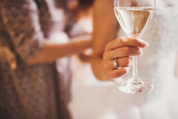 Hand of the bride with a ring and a glass