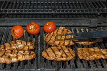 View of cooking meat steak and tomatoes on grill outdoors. Sweden.

