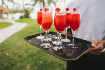 Bright cocktails on a tray in the hands of the waiter