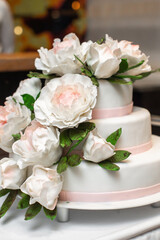 Multilevel wedding cake on the table decorated with roses