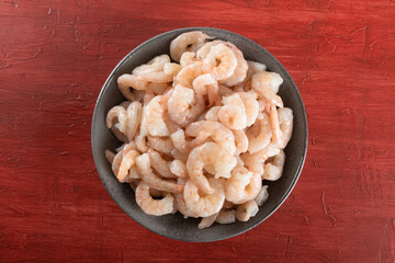 A bowl of peeled fresh raw white shrimp with tail.