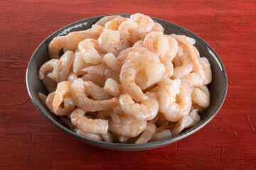 A bowl of peeled fresh raw white shrimp with tail.