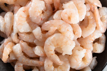 A bowl of peeled fresh raw white shrimp with tail.