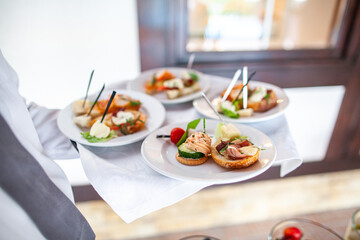 Dishes in round plates in the hands of the waiter