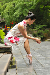 Chinese girl is showing ballet posture at the old buildings alley