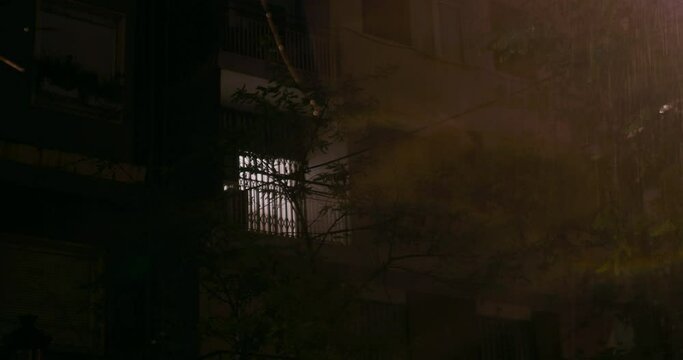 Night rain with lightning, outside view of apartment house with closed windows