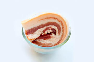 Streaky pork in glass bowl on white background.