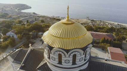 Golden domes of the Orthodox Vladimir Cathedral in Chersonesos, on the background of blue sea. Shot. The largest temple on the Crimean Peninsula. Top view of the temple of Chersonesos