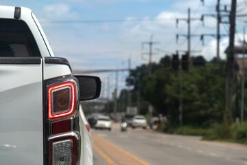 Back side of pick up car white color on the asphalt road. Turn on brake light. with blurred...