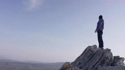 Man on top of the mountain. A young, athletic man stands on a high rock