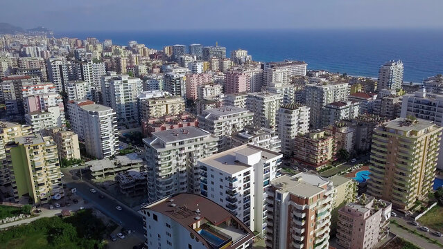 Top View Of Resort Green City On Background Of Sea And Mountains. Clip. Beautiful Landscape With Green Plants Among Resort High-rise Buildings Of City On Coast