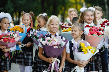 Girls and boys in school uniforms with flowers.