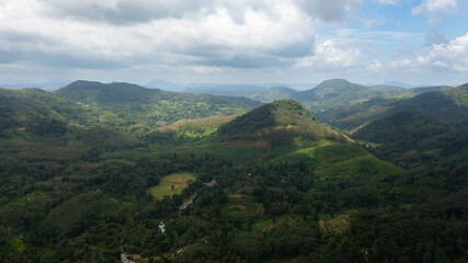 Top view of Mountains covered rainforest, trees and blue sky with clouds. Sri Lanka.