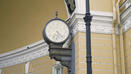 Old clock on facade of yellow building. Action. Street clock protrudes from facade of old building. Clock under arch of General staff in St. Petersburg