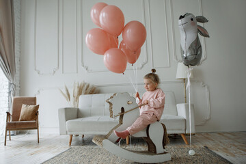Girl with balloons with toy horse in the interior.