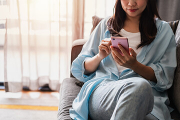 Young woman using mobile phone and relaxing at home, Modern lifestyle and social media concept.