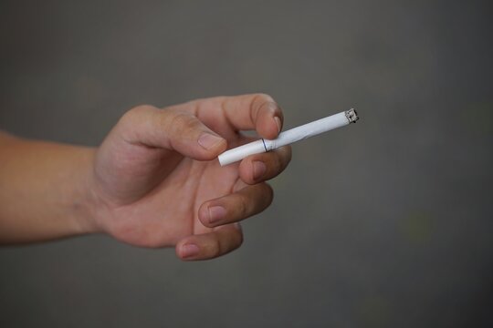 Close up picture of cigarette with hand.