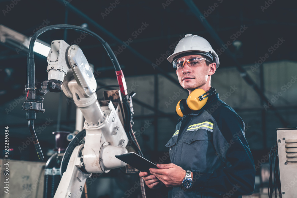 Poster young factory worker working with adept robotic arm in a workshop . industry robot programming softw