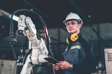 Young factory worker working with adept robotic arm in a workshop . Industry robot programming...