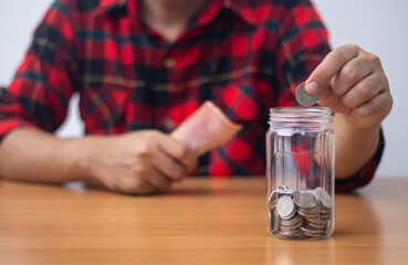 Fototapeta na wymiar Man putting coin in clear plastic jar (Saving concept)