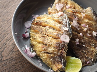 golden crispy deep-fried snakeskin gourami fish served with chopped shallots and lime