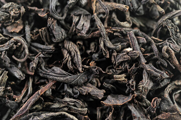 Premium black loose leaf tea as a background. Texture of dry black tea leaves. Extreme macro mode