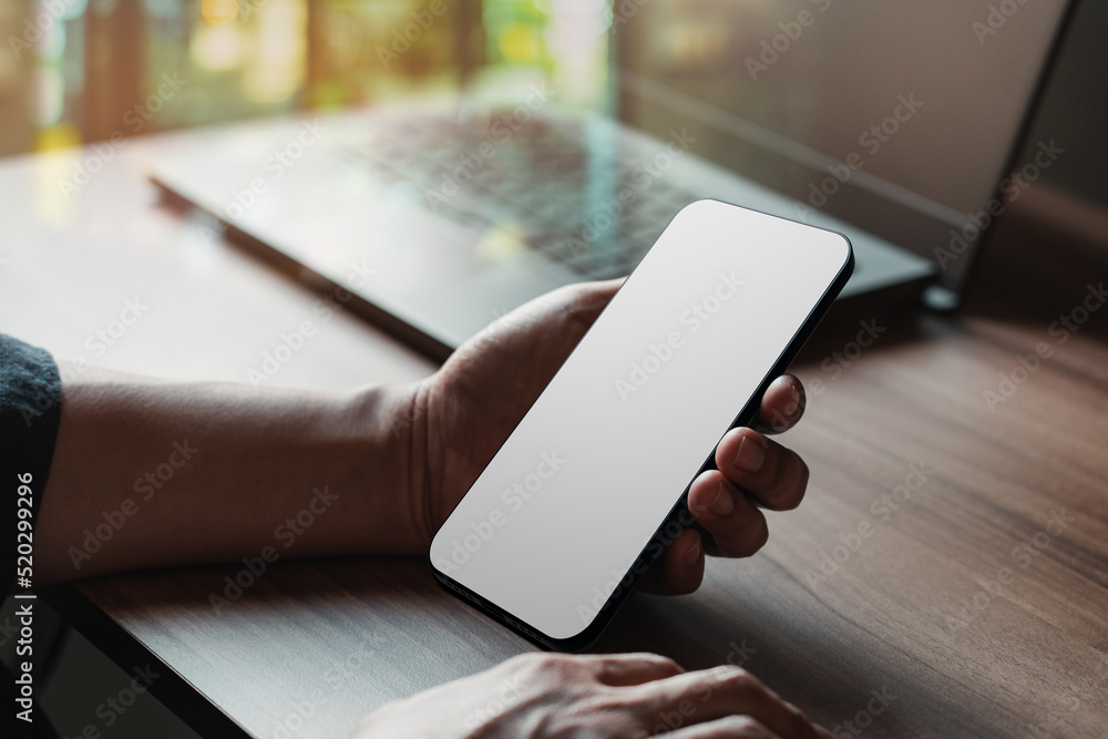 Poster Mockup image of a man holding and using smartphone with blank desktop screen while working and drinking coffee in cafe.