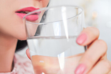 Close up of young woman drinking glass of pure still water