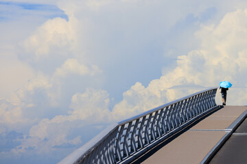 青い日傘を差して橋を渡る人